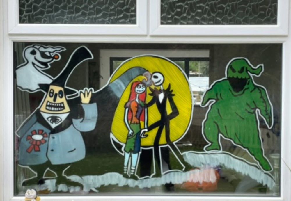 Halloween characters under a big yellow moon, painted on a window