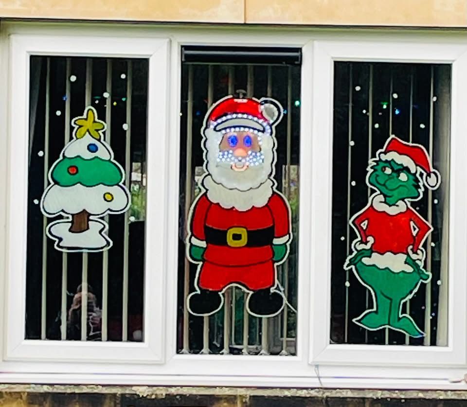 A Christmas tree, Santa and a grumpy green Christmas character painted across three window panes